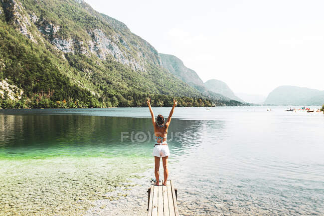 Donna felice che festeggia con le braccia alzate in un lago — Foto stock