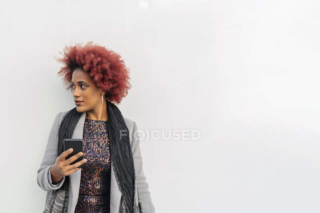 Красивая женщина с афроволосами отправляет сообщение со своего смартфона — стоковое фото
