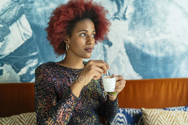 Красивая женщина с афроволосами пьет кофе — стоковое фото
