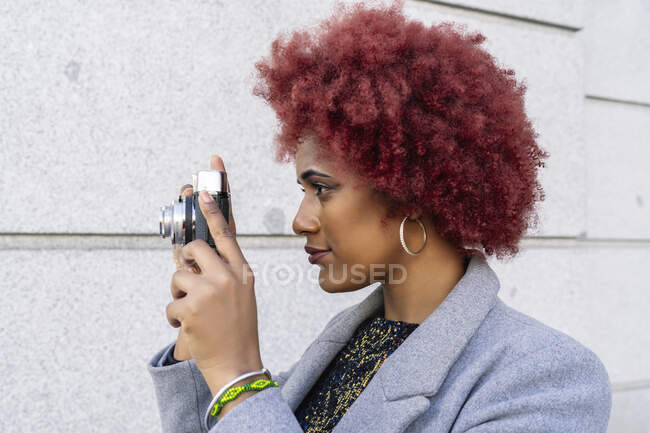 Hermosa mujer con el pelo afro tomar fotos con su vieja cámara - foto de stock
