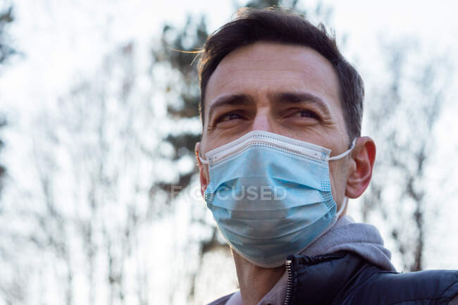 Uomo bianco di mezza età che indossa una maschera medica all'esterno in un vestito sportivo — Foto stock