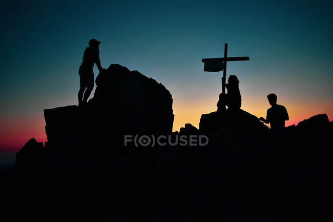 Silueta de un grupo durante la puesta del sol en la cima de las montañas de los corsos - foto de stock