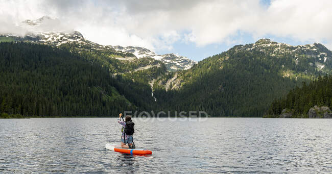 Unrecognizable woman paddleboarding in lake — Stock Photo