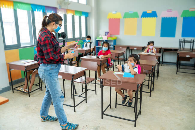 Group of school kids wearing protective mask to Protect Against Covid-19 with teacher sitting in classroom,education,elementary school,Social Distancing,learning and people concept. — Stock Photo