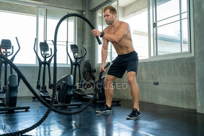 Сильный мужчина тренируется с веревкой в функциональном фитнесе тренировки в тренажерном зале, спортсмен строитель мышц образ жизни. — стоковое фото