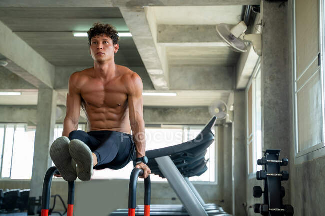 Sportsman faisant de l'exercice sur des barres parallèles dans la salle de gym, Athlete builder muscles lifestyle. — Photo de stock