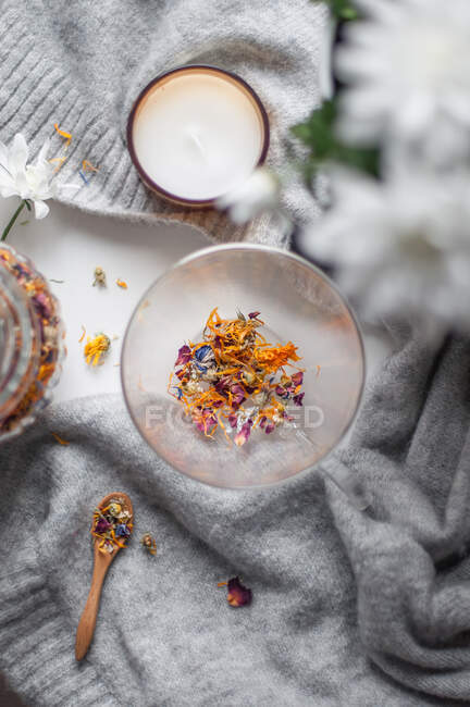 Прозора чашка з сухим квітковим чаєм та дерев'яною ложкою на светрі — стокове фото