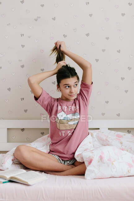 Gir sentado em sua cama e brincando com o cabelo — Fotografia de Stock