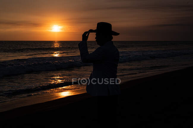 Silhouette di un uomo con cappello davanti al mare al tramonto — Foto stock