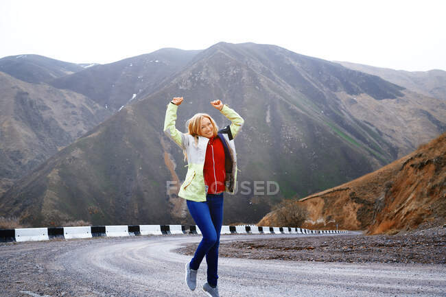 Mujer viajera baila en el camino de la montaña - foto de stock