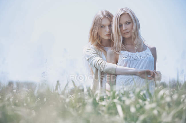 Two women hugging in the grassland. Nicely fits for book cover — Stock Photo