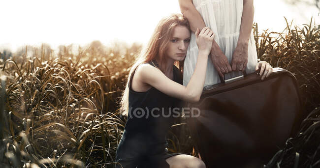 Donna triste appoggiata alla sorella che tiene la valigia sul campo. Molto bene. — Foto stock