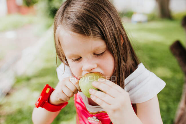 Niedliches kleines Mädchen mit Apfel im Park, Sommer — Stockfoto