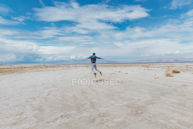 Persona che salta sulla spiaggia - concetto di levitazione. Giornata ventosa — Foto stock