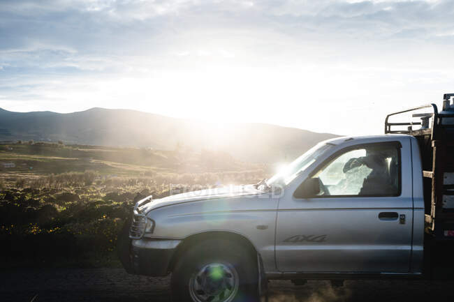 Двоє людей в машині, що подорожує по сільській місцевості з заходом сонця — стокове фото