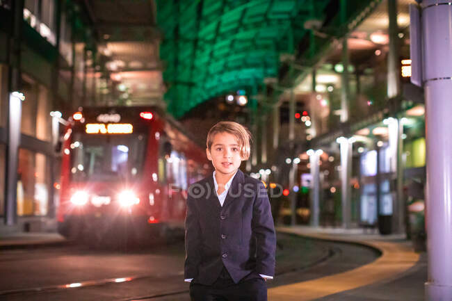Niño usando traje de pie en la estación de tren en el centro. - foto de stock