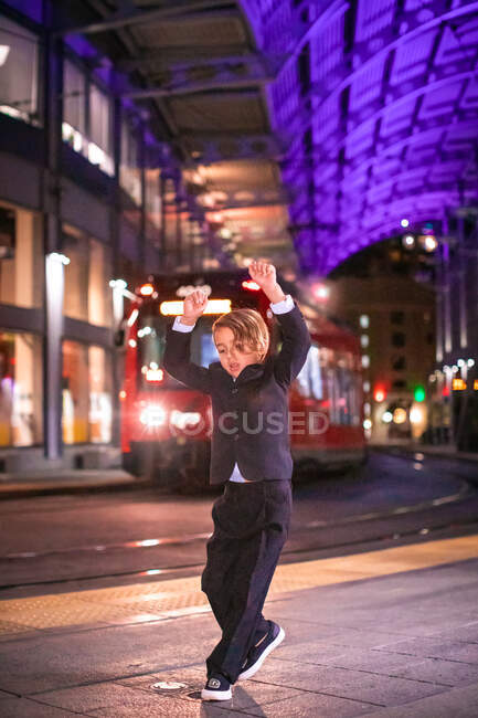 Boy dancing at a Downtown train station at nigh time. — Stock Photo