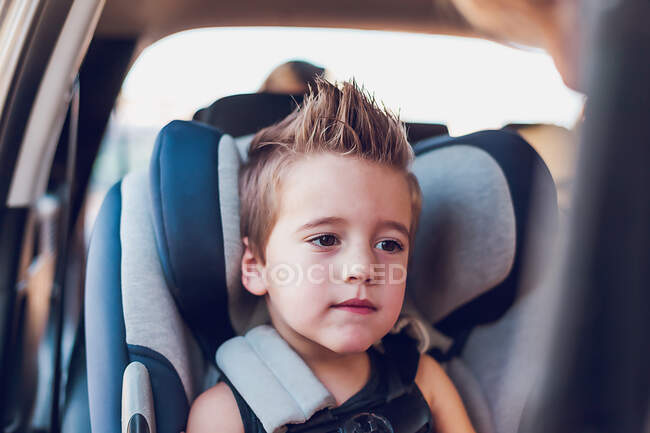 Menino em idade pré-escolar sentado no assento do carro dentro de um carro. — Fotografia de Stock