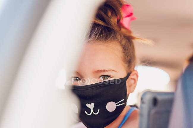 Jeune fille avec de jolis yeux portant un masque de chat dans une voiture. — Photo de stock