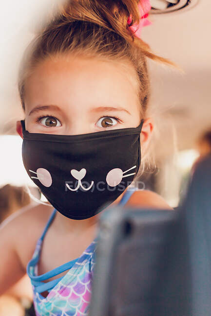 Chica con ojos bonitos mirando a la cámara y con una máscara de gato. - foto de stock