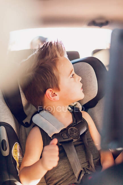 Ragazzo in età prescolare seduto in un seggiolino auto all'interno di una macchina. — Foto stock