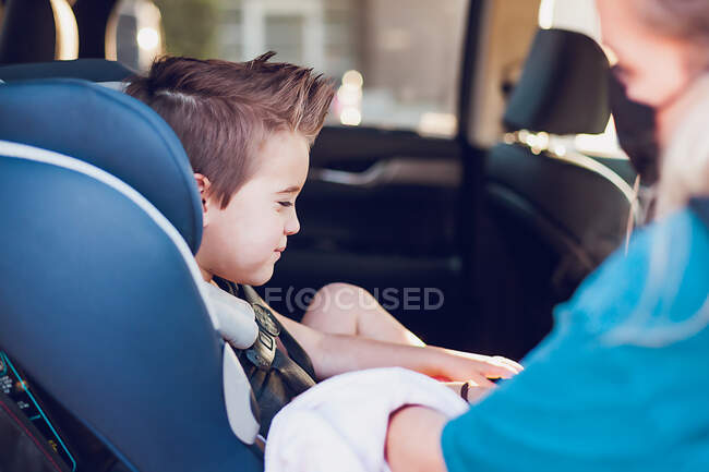 Mother removing her young son from car seat. — Stock Photo