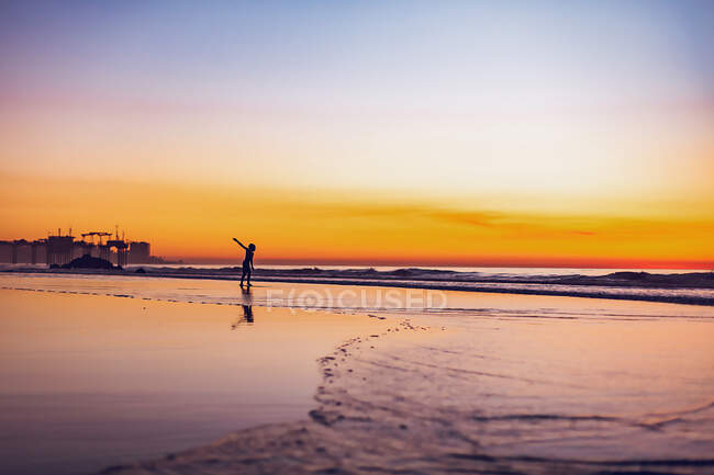 Junge spielt in der Abenddämmerung im Wasser am Strand. — Stockfoto