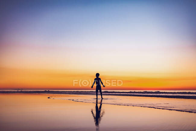 Jovem rapaz ao pôr do sol na praia — Fotografia de Stock