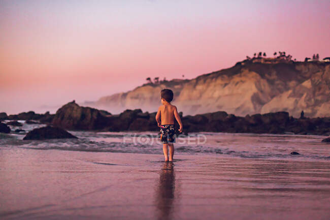 Jovem rapaz ao pôr do sol na praia — Fotografia de Stock