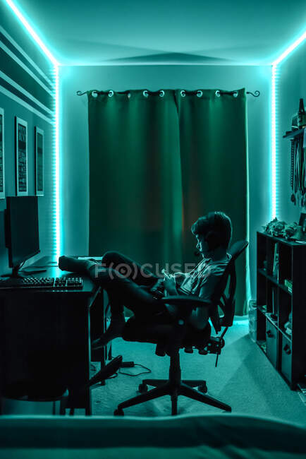 El muchacho joven con el ordenador en la habitación - foto de stock