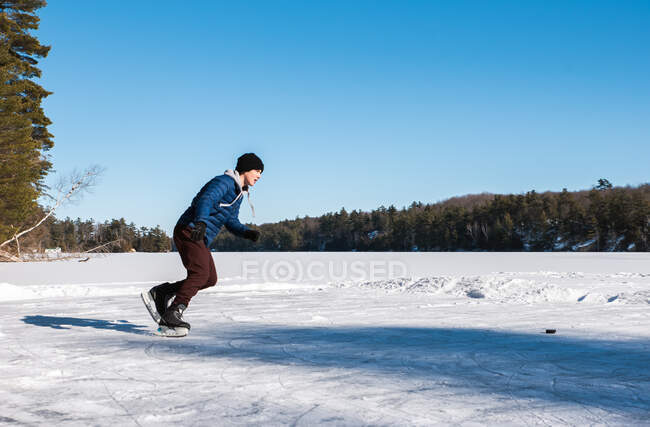 Adolescente menino patinação no gelo em um lago congelado em um dia de inverno no Canadá. — Fotografia de Stock