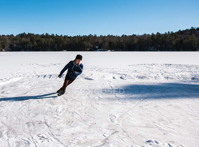 Adolescente niño patinaje sobre hielo en un lago congelado en un día de invierno en Canadá. - foto de stock