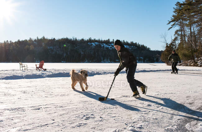 Padre e hijo jugando hockey en pista al aire libre en el lago canadiense congelado. - foto de stock