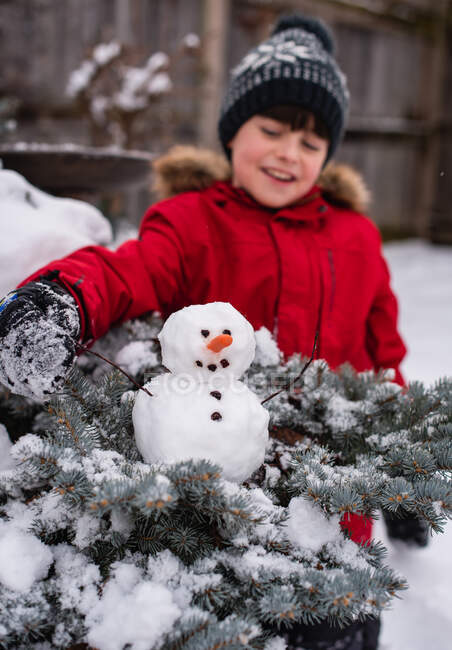 Der Junge mit dem Schneemann im verschneiten Wald — Stockfoto