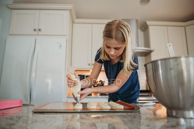 Chica joven tubería macarrones en la cocina - foto de stock