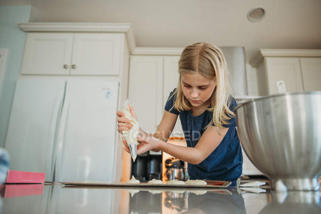 Menina nova assar macarons na cozinha — Fotografia de Stock