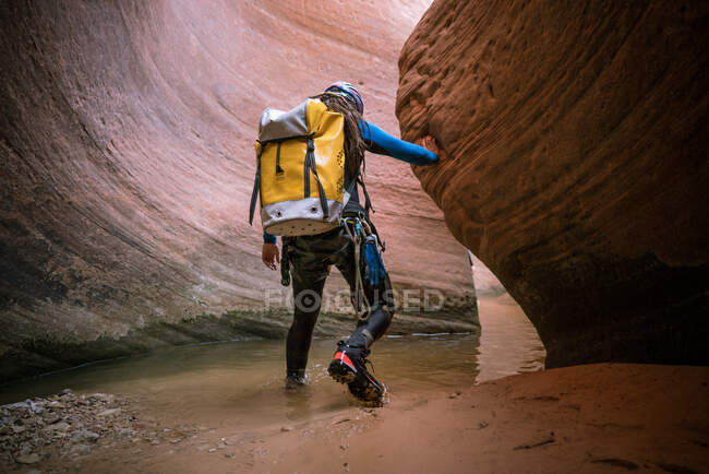 Молодий чоловік входить у глибоку воду всередині вузького щілинного каньйону — стокове фото