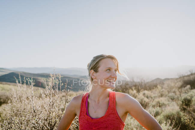 Atlética rubia ríe con sol y montañas detrás de ella - foto de stock