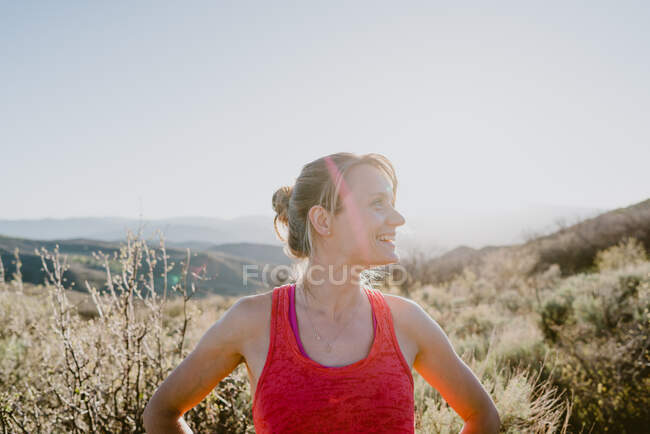 Athletische blonde Frau lacht mit Sonne und Bergen im Rücken — Stockfoto