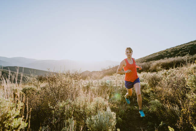 Trilha de mulher loira atlética corre nas montanhas na hora de ouro — Fotografia de Stock