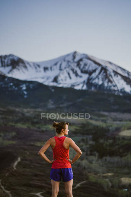 Junge Frau blickt im Morgengrauen auf die Berge — Stockfoto