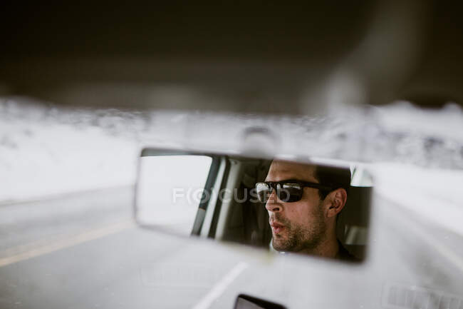 A man is seen whistling to music in the rear view mirror of his van — Stock Photo