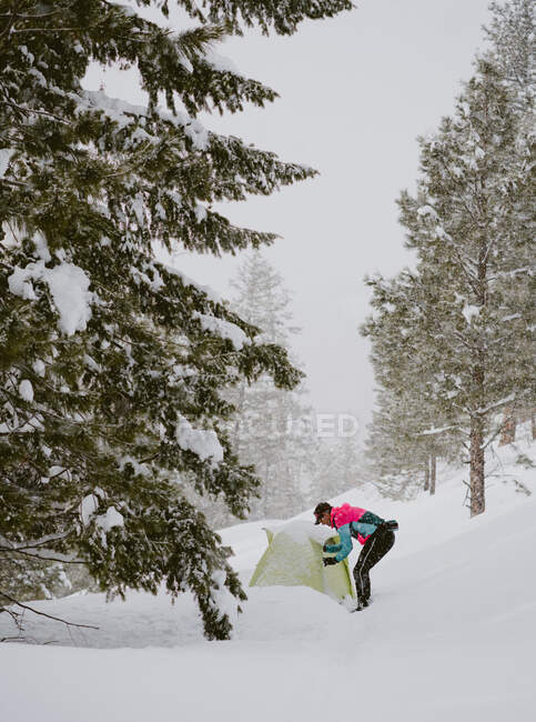 Un uomo in giacca luminosa sta fuori tenda nella neve profonda — Foto stock