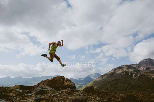 Um homem salta para o ar em frente à paisagem montanhosa — Fotografia de Stock