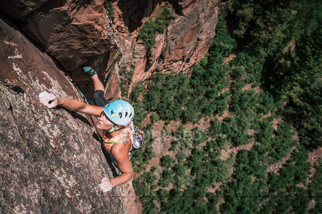 Жіночий альпініст тримає креветки, але залишається зосередженим високо на стіні — стокове фото
