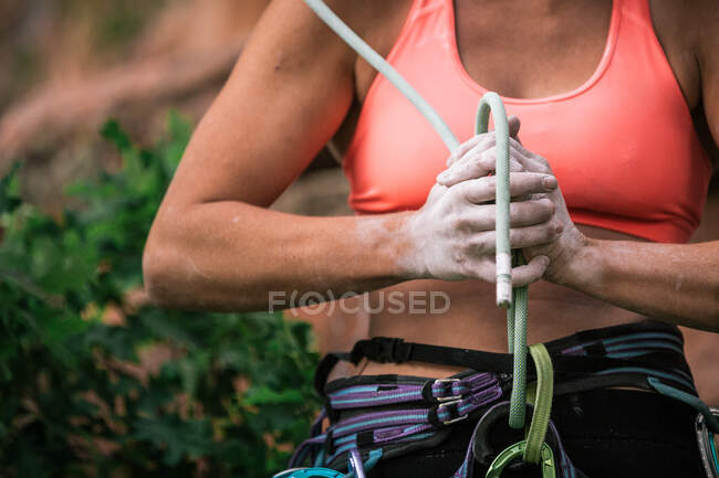 Woman presses figure eight knot with chalked hands after lead climb — Stock Photo