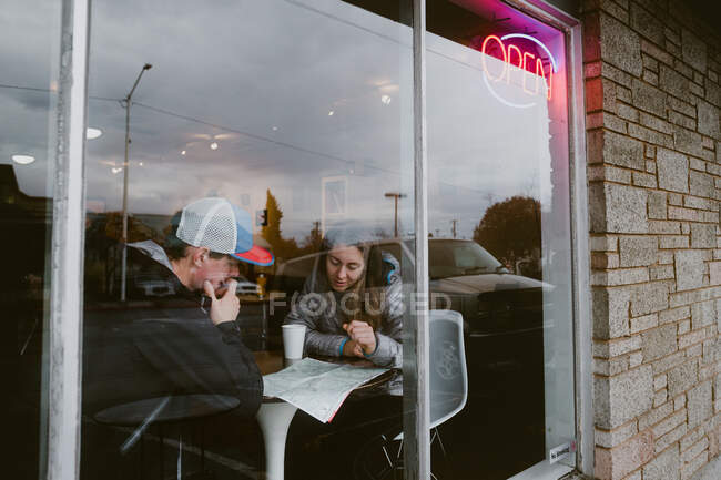 Friends sit at coffee shop together and plan their next adventure — Stock Photo
