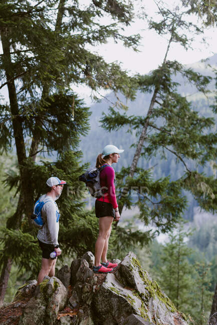 Female and male trail runners stop to take in the view of mountains — Stock Photo