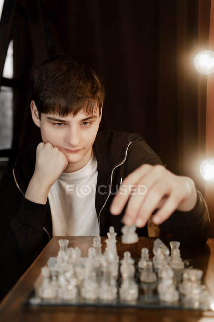 Young guy playing glass chess — Stock Photo
