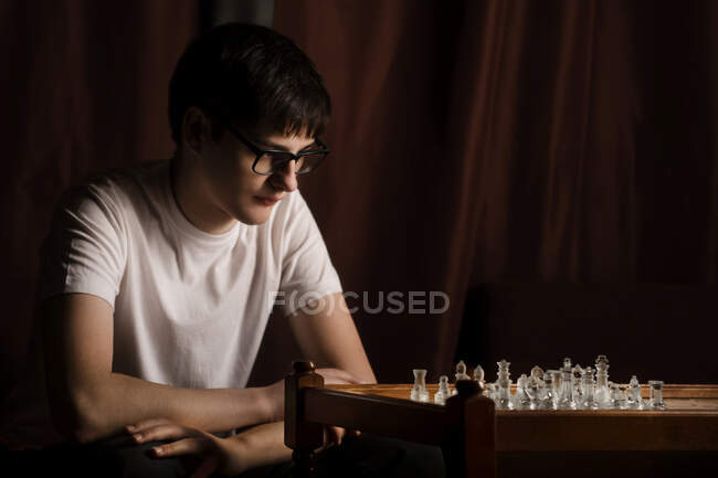 Guy en pose fermée pensant à un mouvement d'échecs — Photo de stock